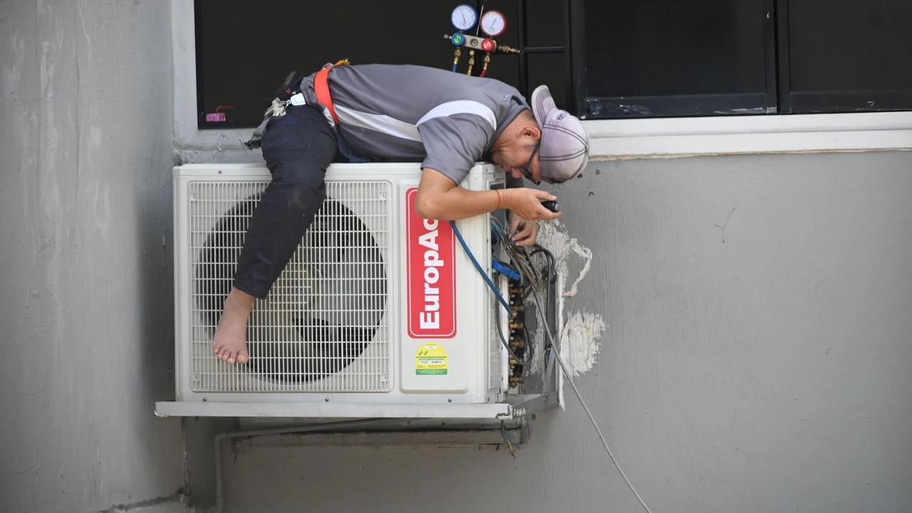Professional AC technician washing a dusty AC filter in a Dubai villa bathroom