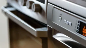 Professional kitchen cleaner detailing oven vents and stove burners with a steam wand