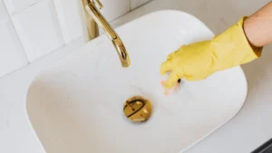 Professional cleaner scrubbing a modern home bathroom glass sink basin