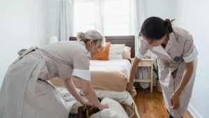 Professional housekeeper changing bed linens and making a neat bedroom bed