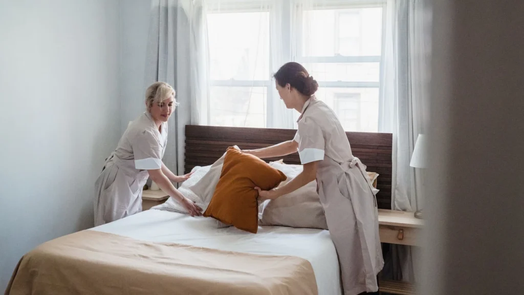 Professional female housekeeper dusting furniture in a modern Dubai bedroom