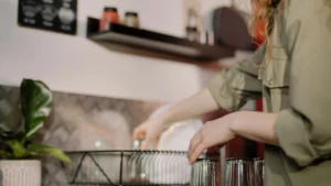Professional housekeeper cleaning kitchen sink fixtures and washing dishes