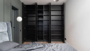 Professional cleaner dusting inside empty wardrobes and bedroom shelves