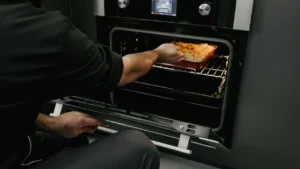 Professional technician cleaning oven inside walls with steam wand
