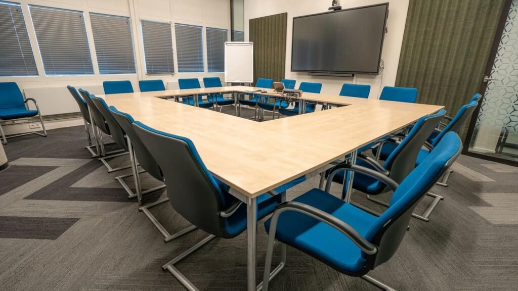 Professional corporate janitor vacuuming carpet floor in an executive office boardroom in Dubai