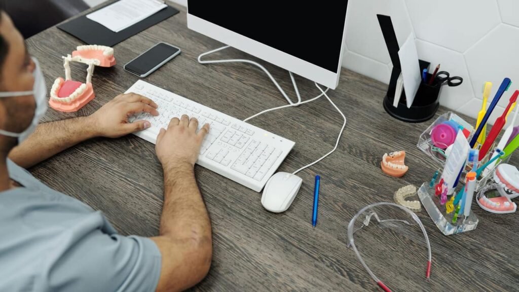 Professional office janitor sanitizing computer keyboards and office desks with a microfibre cloth