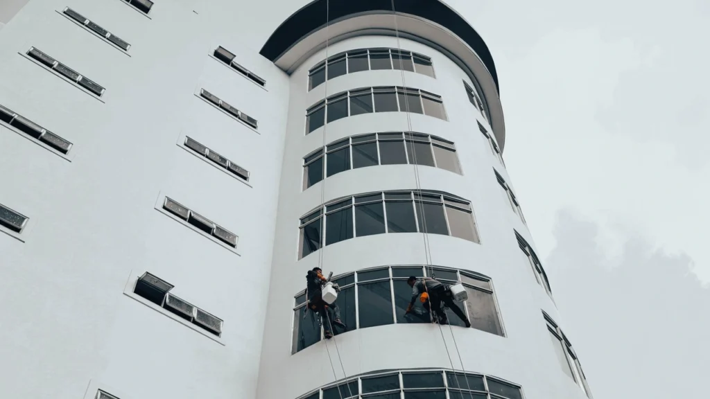 High-rise window cleaner wiping glass panels with a squeegee in Dubai