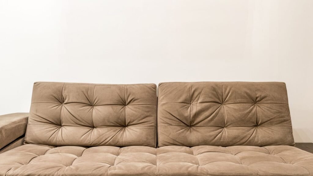 Professional upholstery cleaning technician extracting water and dirt from sofa cushion using steam extraction wand