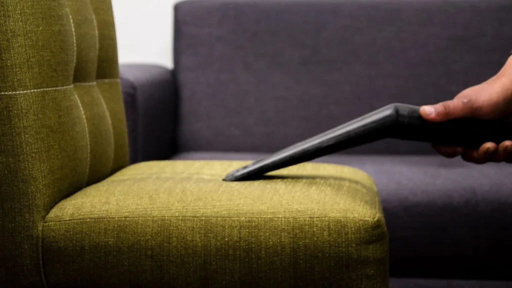 Upholstery technician deep steam cleaning a fabric sofa in a living room in Dubai